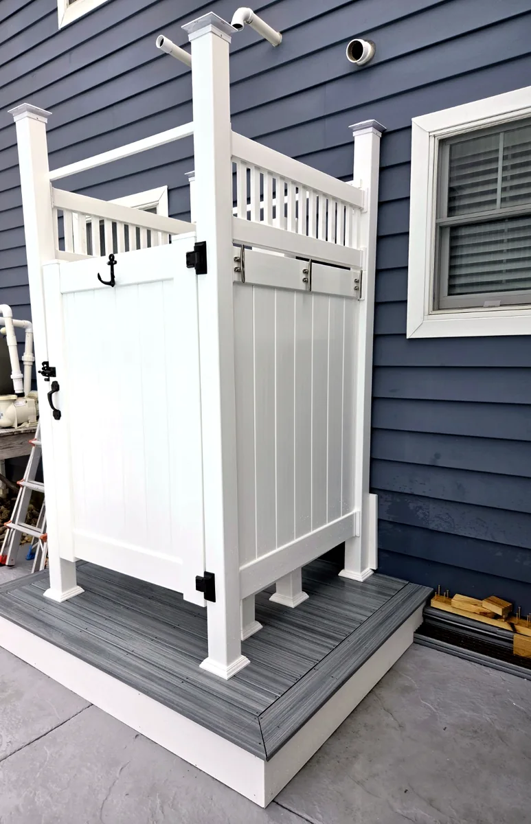 Finished white vinyl outdoor shower enclosure on custom platform